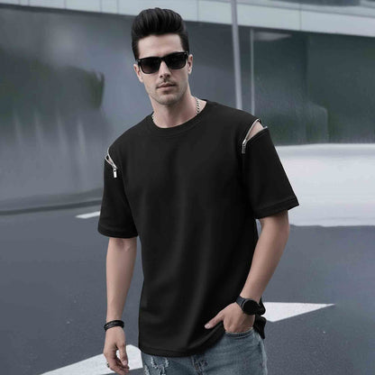 Man wearing a black t-shirt with unique arm design, sunglasses, and jeans on a blurred street background.